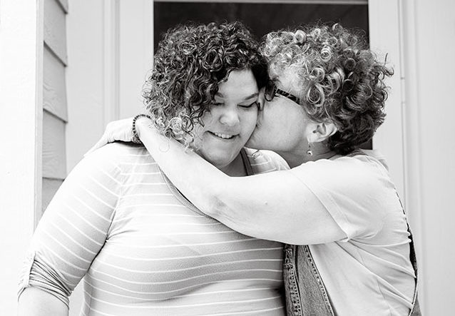 mom kissing daughter with love on cheek